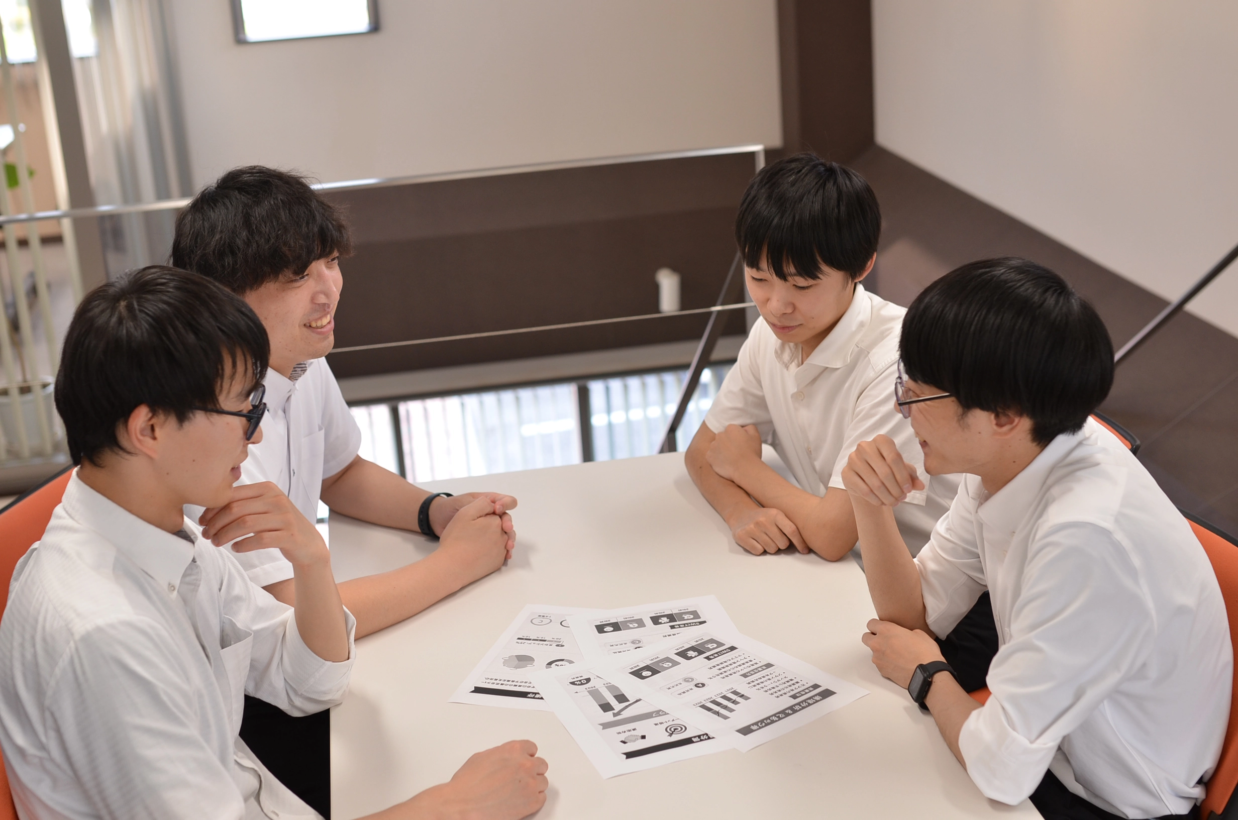 若手社員がノートパソコンを囲み、笑顔で話し合っているイメージ